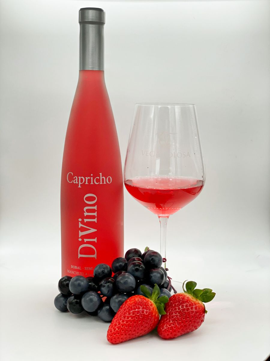 Una elegante botella de vino rosado acompañada de un racimo de uvas y fresas frescas, mostrando un producto de calidad.